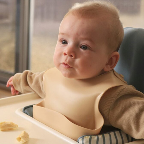 Baby who has just started eating looking at piece of banana